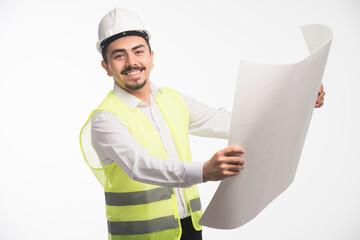 Engineer in uniform holding and reading the architectural plan of the construction