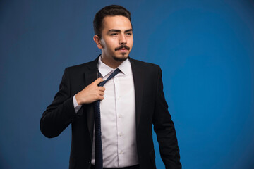 Businessman in black suit taking out his tie