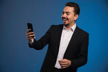 Businessman in black suit checking his telephone