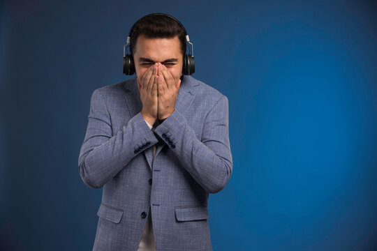 Male dj in grey suit listening to headphones