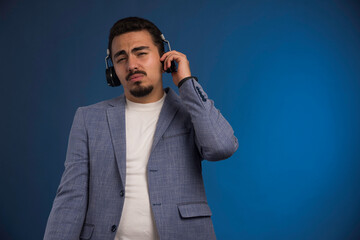 Naklejka premium Male dj in grey suit listening to headphones