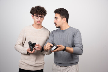 Two young men showing a camera on a white background