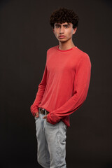 Young model in red shirt posing by putting hands on his pockets