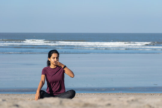 Woman doing yoga Anulom Vilom, breathing on beach. Jogging, workout, exercise, healthy life, diet, lifestyle, sedentary, active, fresh, fitness, periods, sunlight, muscle, work life balance concept.