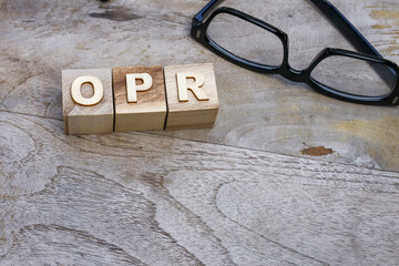 Close up view of OPR wordings on the wooden blocks with an eyeglasses on the wooden table