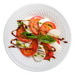 Caprese salad with mozzarella and tomato with basil and balsamic and pesto sauce on white plate top view isolated on white background