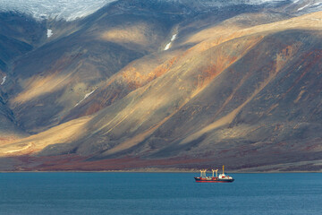 Cargo ship in the bay. Epic arctic landscape. Beautiful mountains on the coast. Sea freight and...