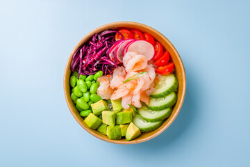 Poke with shrimps, avocado,edamame, cabbage, tomatoes and cucumbers on blue background top view