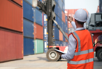 Foreman points to control the loading position of containers from big forklift.Import and export cargo freight concept.
