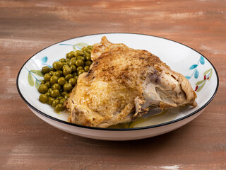 Baked chicken and green canned peas and on a plate with a pattern