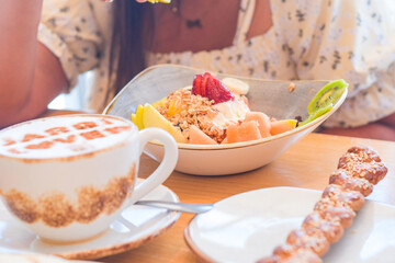 Cup of coffee, plate of fruits and pastries in a cafeteria unrecognizable person.