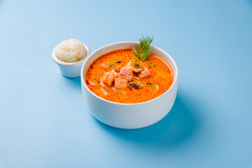 Tom Yam soup with salmon on blue background