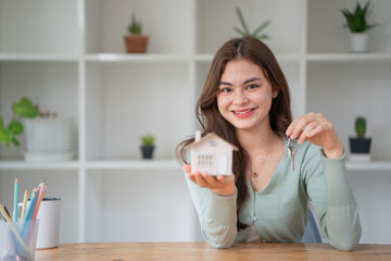 Woman holding white house model and house key in hand.Mortgage loan approval home loan and insurance concept.