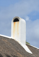 Chimney designed on the roof of a house or building outside against a cloudy sky background with...