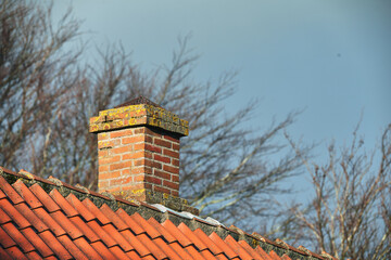 Red brick chimney designed on asbestos slate roof of house building outside with a sky background....
