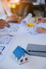 Close up of hands working and brainstorming on paperworks and floor plan drawings about design architectural and engineering for houses and buildings. focus on house model.