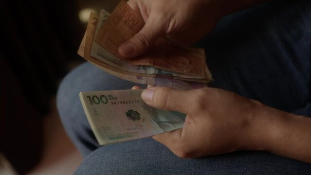 Colombian saver is accounting his savings in a full collection of colombian pesos bills and exchange them for one bill of one hundred us dollar to protect his finances against inflation