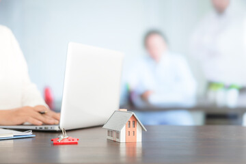 Businesswoman choosing mini house model from model on wood table