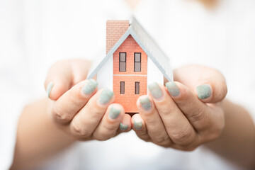 woman holding a house model with two hands