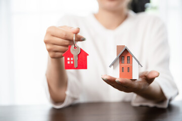 Woman holding house model and house key in hand