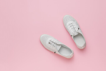 Sporty white shoes on a pink background. Minimal concept of beauty and sports.