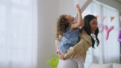Family Asian mother and child daughter on a piggy back ride with his mother at home,mom and daughter play piggy back ride fun game in birthday celebrate party together at home
