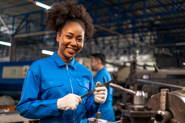 African American Young woman worker  in protective uniform operating machine at factory...