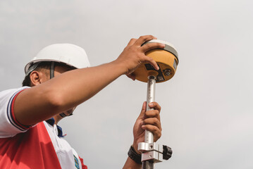 A surveyor sets up a Global Navigation Satellite System or GNSS Receiver. Real-time kinematic or RTK geodetic surveying equipment used in the field.