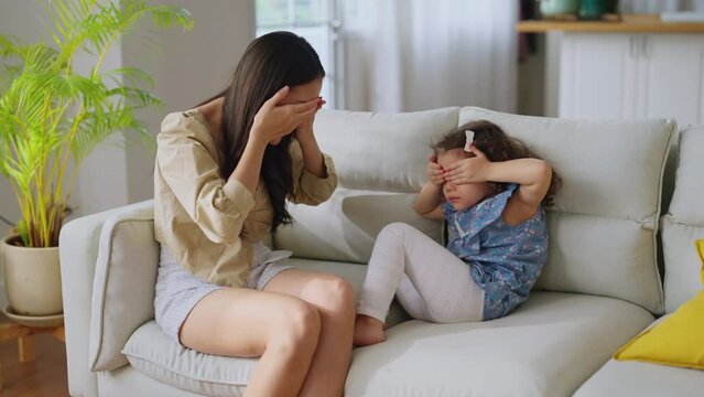 happiness cheerful Mother and child girl are playing peekaboo or peek-a-boo on a sofa couch and having fun in living room at home,fun and joyful sunday morning lifestyle mom and daughter play together