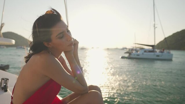 4K Attractive Latin woman enjoy luxury outdoor lifestyle while catamaran boat sailing in the sea at summer sunset. Beautiful female relaxing on private sail yacht on tropical holiday travel vacation