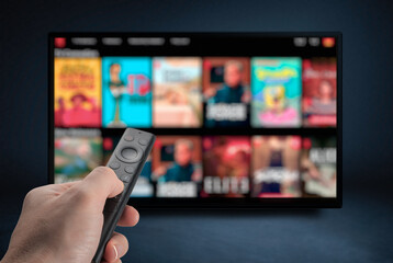 Tv online. Television streaming video. Male hand holding TV remote control. Multimedia streaming concept. VoD content provider. Video service with internet streaming multimedia shows, series. - obrazy, fototapety, plakaty