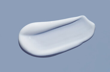 White cosmetic cream lotion swatch smear smudge on blue color background. 