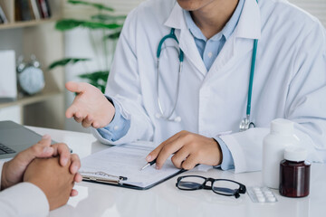 Asian doctor is examining the abnormal items of the body and diagnosing the disease in the paper with the medical report of the patient..