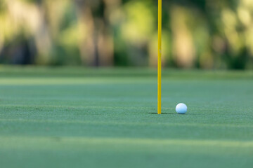 Golf ball near a flagstick on a golf course.