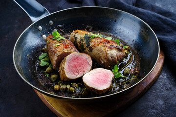 Traditional fried duroc pork fillet pieces with capers and spices served as close-up in a rustic skillet © HLPhoto
