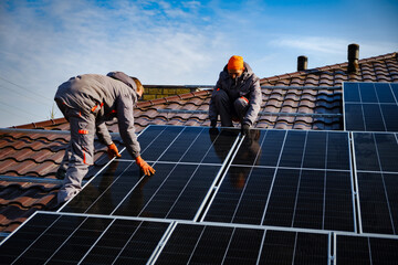 Engineers on the roof of house are checking solar cells in the autumn. Technician worker on solar...