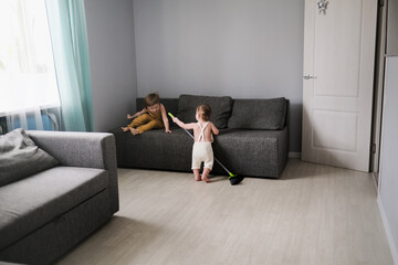 Children siblings with mop clean in real bright living room