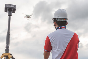 A surveyor operating a drone to conduct topographic RTK or PPK aerial survey or photography of a...
