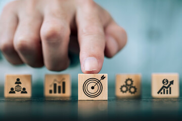 Businessman hand arranging wood block with business goal symbol ideas , Planning for goals against business success , Business strategy and marketing target concept