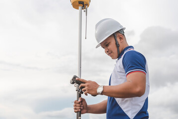 An asian male land surveyor operating a GNSS receiver. Using RTK geodetic surveying equipment. © Mdv Edwards
