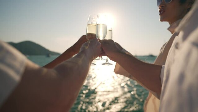 Caucasian man and woman enjoy luxury outdoor lifestyle celebrating holiday party and toasting champagne glass together while catamaran yacht boat sailing in the sea at summer sunset on travel vacation