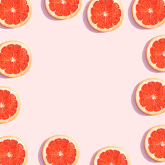 Red sliced grapefruit on a pastel pink background. Restangle frame. Summer aesthetic fruit concept.