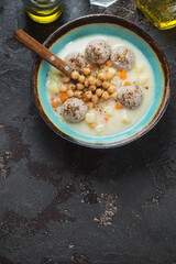 Turquoise bowl with chickpea and meatball soup, above view on a brown stone background, vertical shot with copyspace