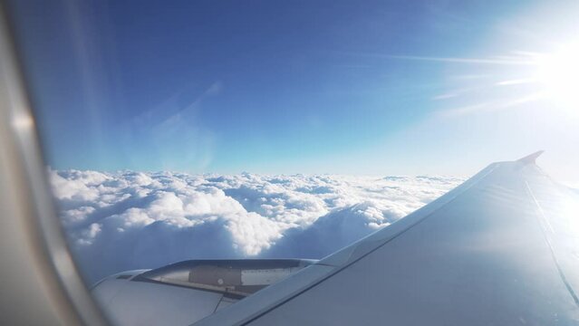 Beautiful view from window of plane on wing. Clear blue sky and white clouds from height. Flying in passenger airplane. Traveling in transport. Commercial airliner. Air travel. Tourism weekend.