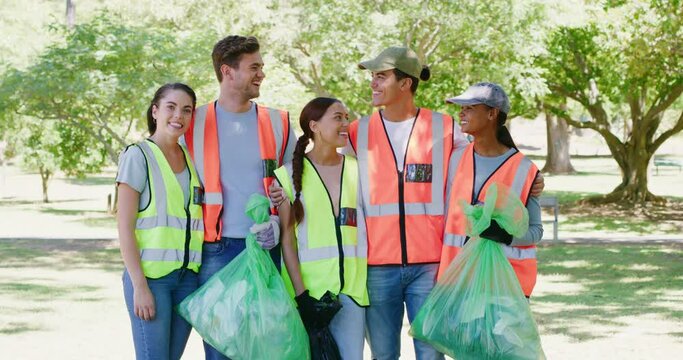 Diverse group of responsible activists and volunteers collecting litter for a sustainable and clean environment. Portrait of happy young people doing charity and community service by cleaning a park