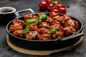 Meatballs in sweet and sour tomato sauce. in frying pan on dark background