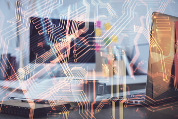 Computer on desktop in office with technology theme hologram. Double exposure. Tech concept.