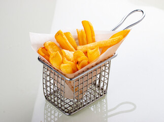 French fries in metal wire basket isolated on a white background