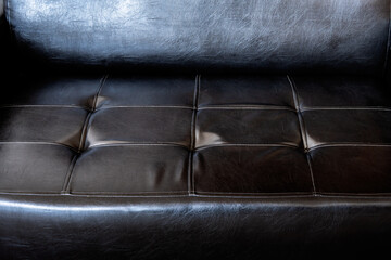 Seat of an old black leather sofa close up