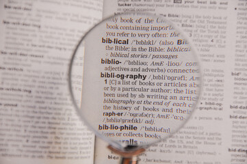 The definition of the word Bibliography in a dictionary, under magnifying glass, translator and...